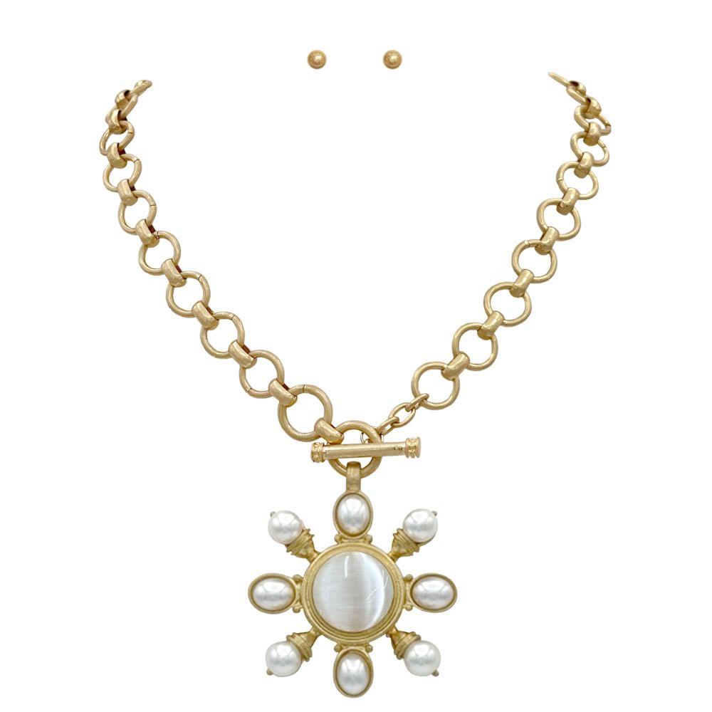 Gold necklace with a sun-shaped pendant featuring pearls on a white background