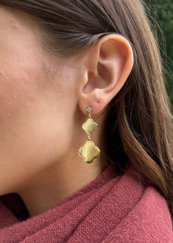 Close-up of a person wearing gold earrings with a blurred background