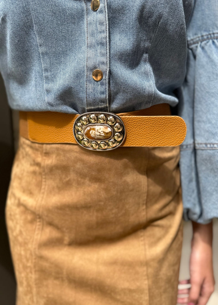 Person wearing a denim shirt and brown skirt with a decorative belt.