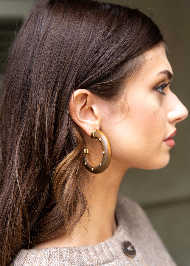 Close-up of a woman wearing gold hoop earrings with a blurred background