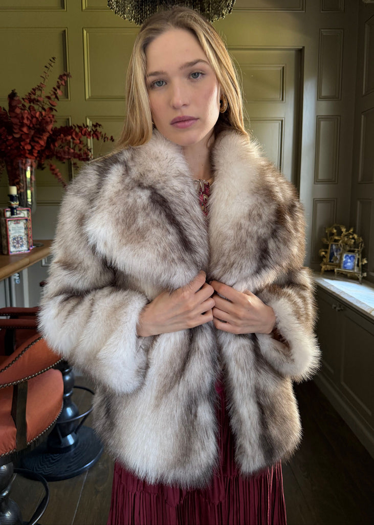 Woman wearing a fur coat in an indoor setting with decor elements.