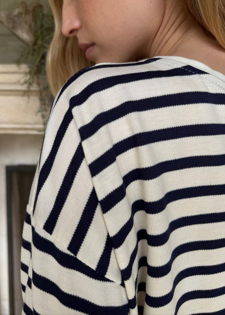 Person wearing a navy and white striped shirt with a fireplace in the background