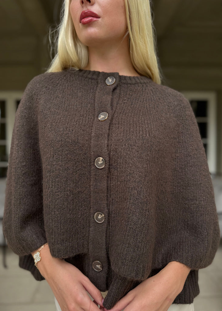 Woman wearing a brown cardigan with a blurred background