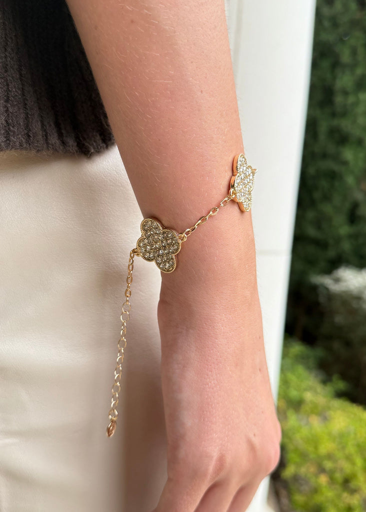 Gold bracelet on a wrist with a blurred green outdoor background