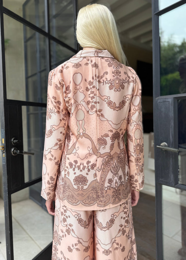 Person wearing a pink patterned outfit standing in front of glass doors.