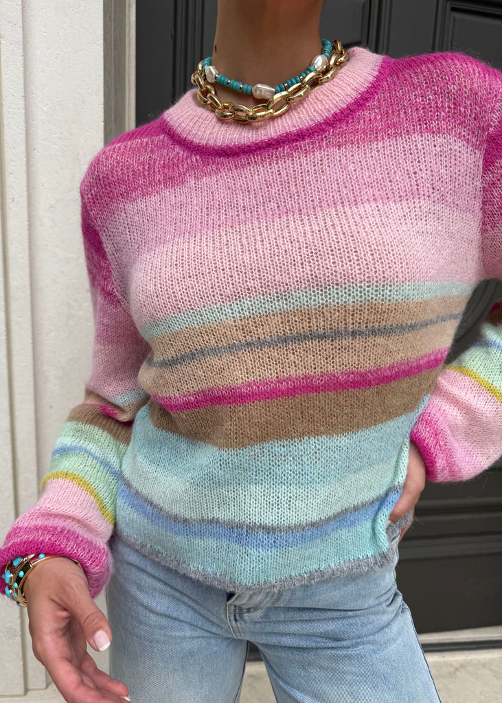 Person wearing a colorful striped sweater with a neutral background