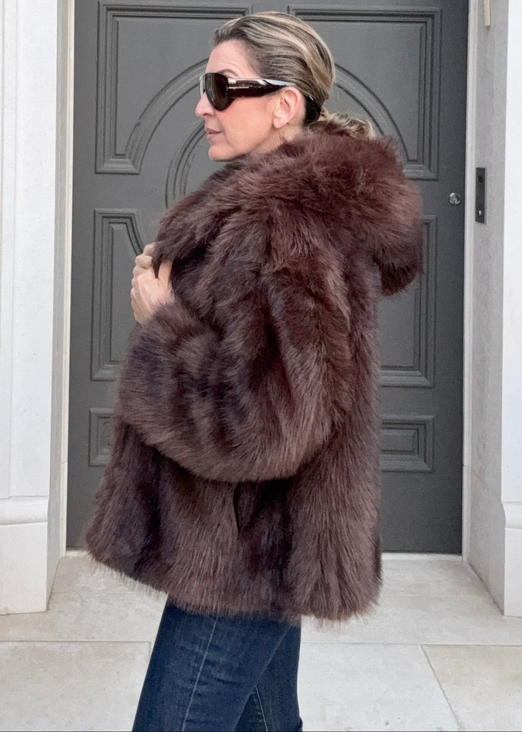 Person wearing a fur coat standing in front of a door
