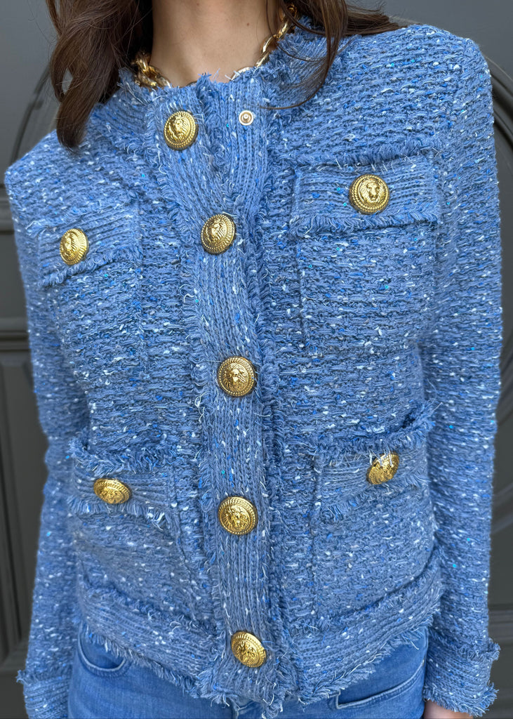 Blue textured jacket with gold buttons on a neutral background