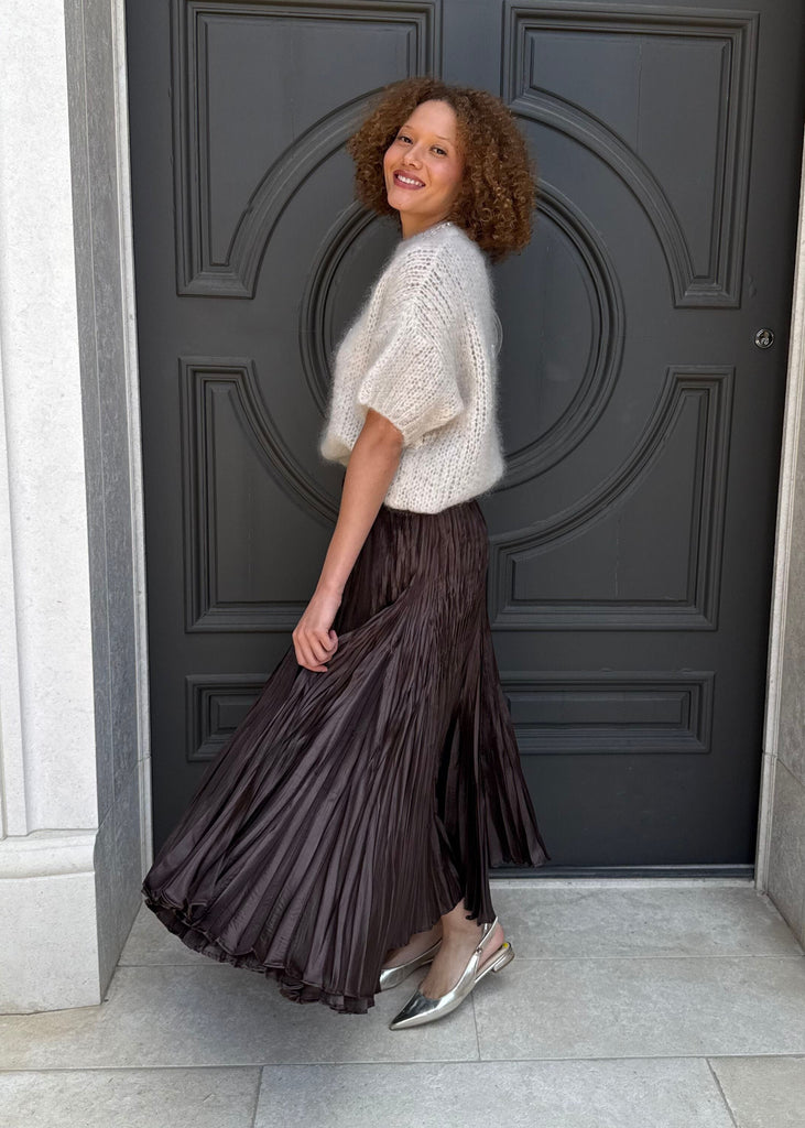 Woman standing in front of a large black door with white walls.