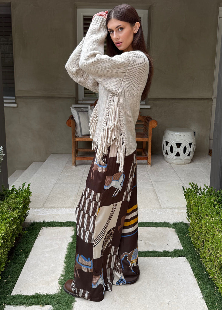 Woman in a patterned dress standing in a garden with a building in the background