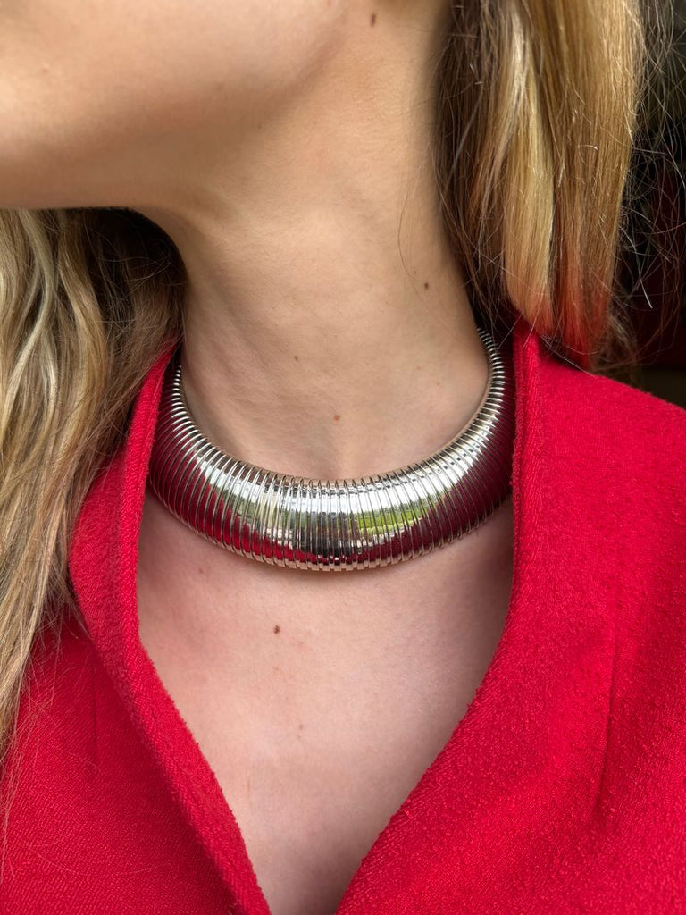 Silver necklace worn by a person with a red garment