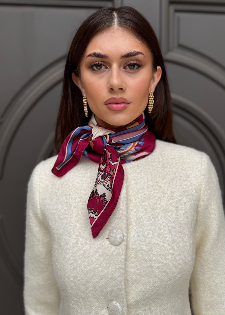Woman wearing a colorful scarf around her neck against a gray door background