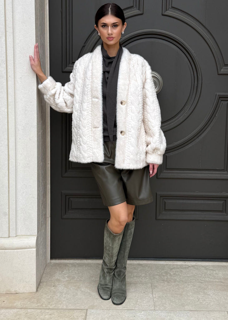 Woman standing in front of a large black door with white columns.
