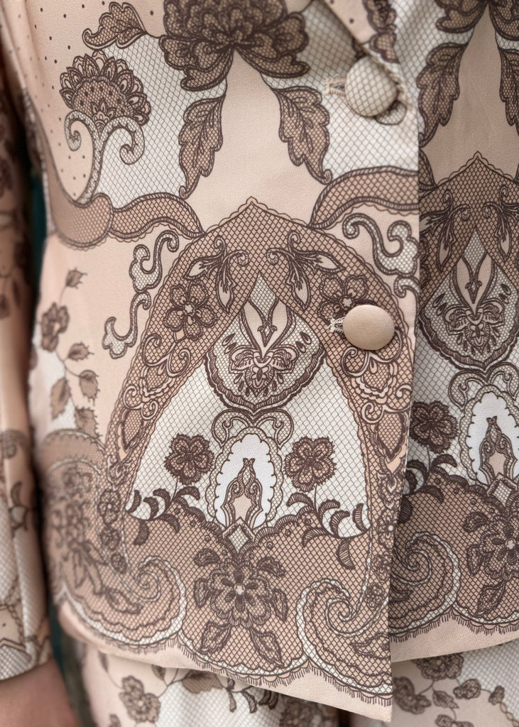 Close-up of a patterned fabric with intricate designs on a beige background