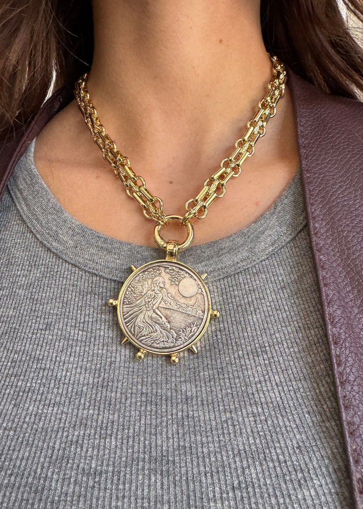 Gold chain necklace with a detailed pendant worn by a person
