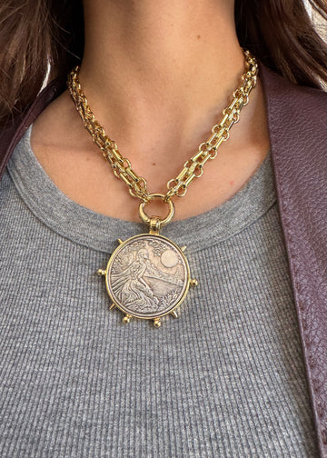 Gold chain necklace with a detailed pendant worn by a person