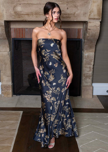 Woman in a strapless floral dress standing in front of a stone fireplace.