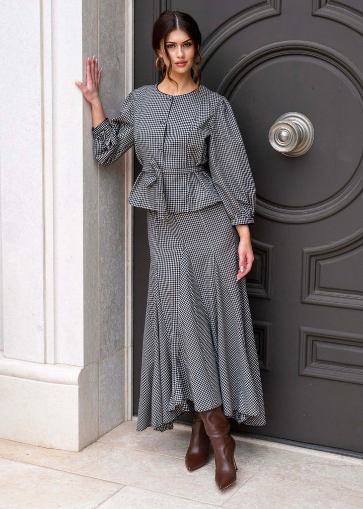 Woman in a gray outfit standing in front of a dark gray door.
