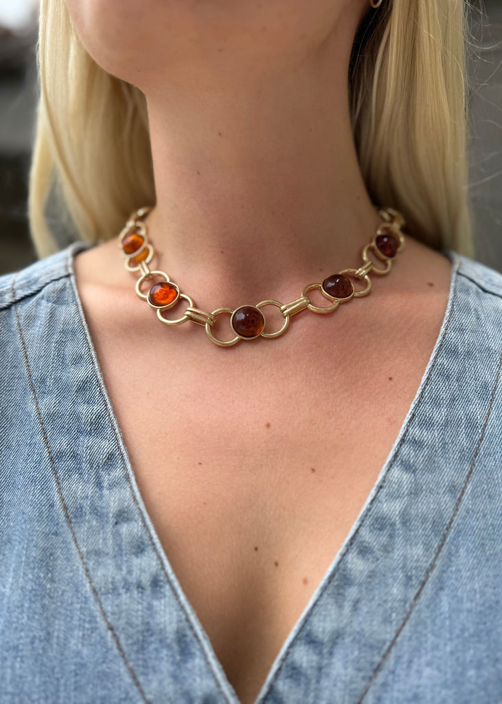 Necklace with amber beads worn by a person in a denim outfit