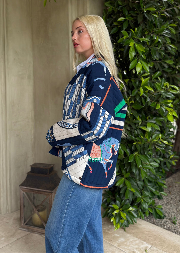 Woman wearing a colorful sweater with a nature-themed design, standing outdoors.