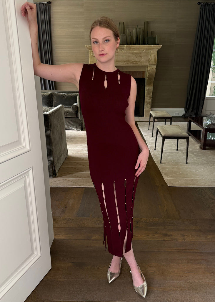 Woman in a burgundy dress standing in a stylishly decorated room.