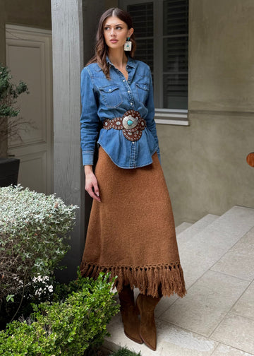 Woman standing in a patio area with a building and bench in the background