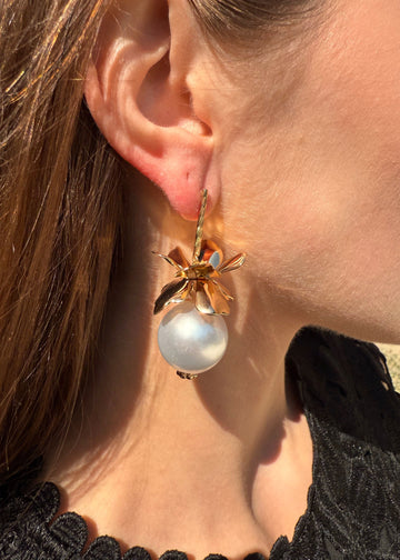 Close-up of a pearl earring worn by a person with brown hair.
