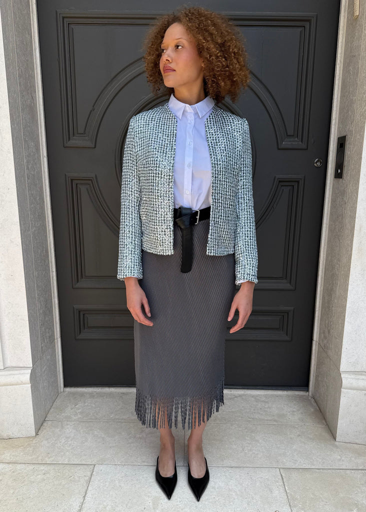 Woman in professional attire standing in front of a dark door.