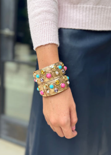 Person wearing a colorful beaded bracelet on a blurred background