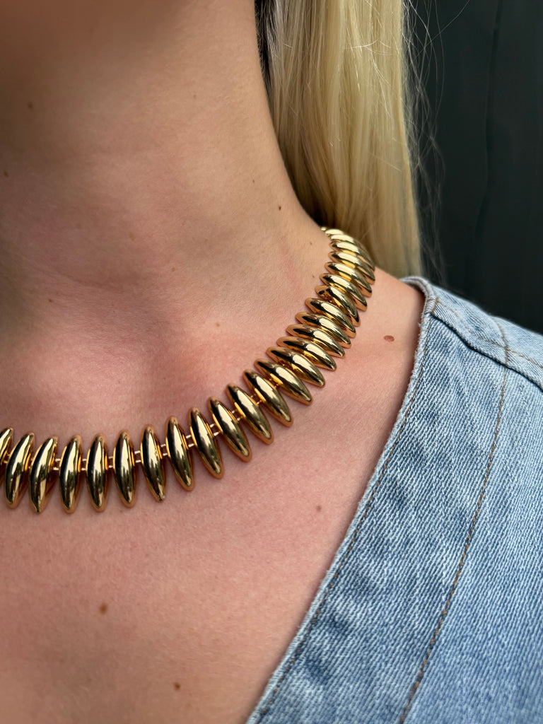 Gold necklace worn by a person with denim clothing