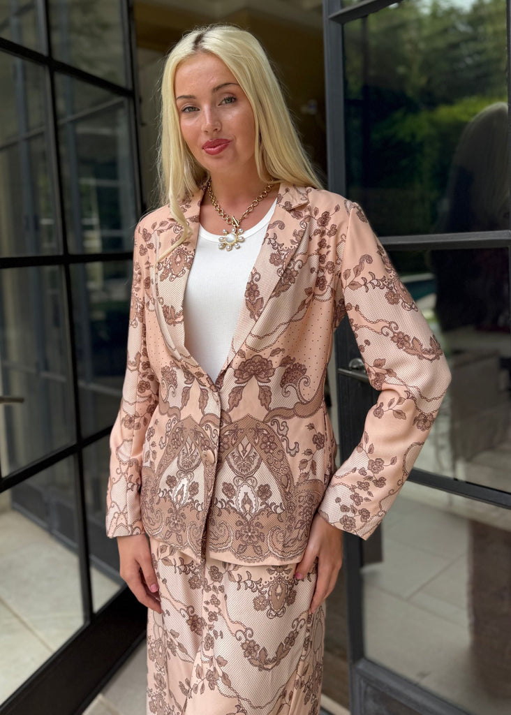 Woman in a floral suit standing in front of a glass door.