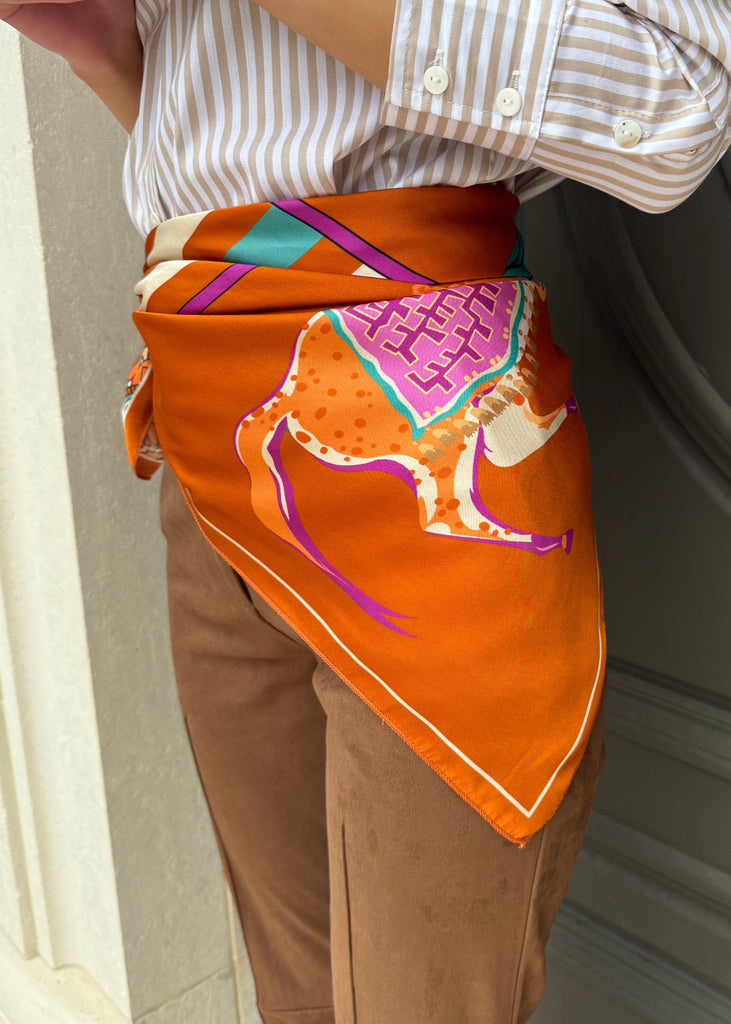 Person wearing a colorful apron with geometric patterns in front of a neutral background