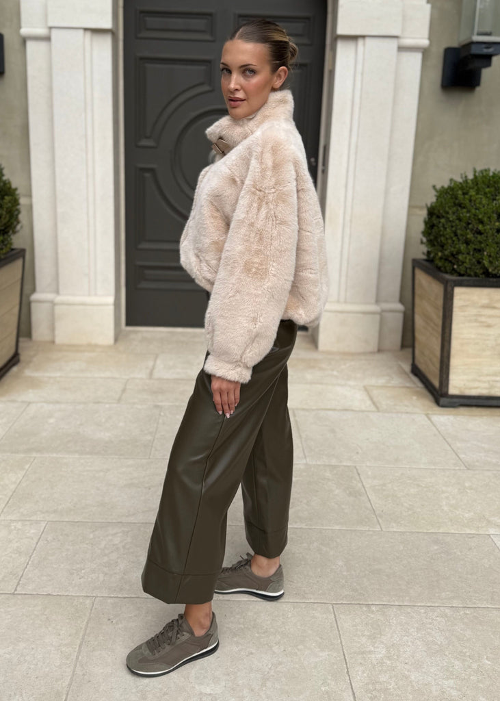 Woman in a fur coat standing in front of a building entrance