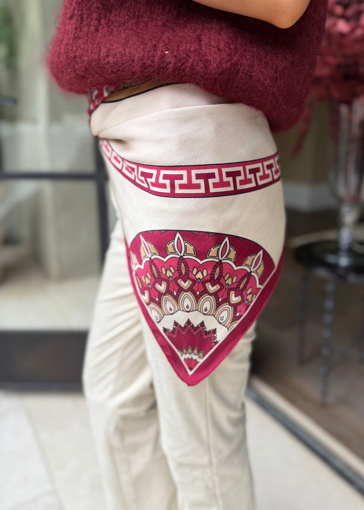 Person wearing a maroon sweater and white pants with red and gold patterns.