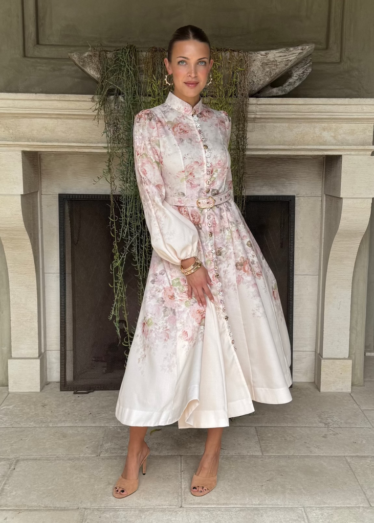 Woman in a floral dress standing in front of a fireplace