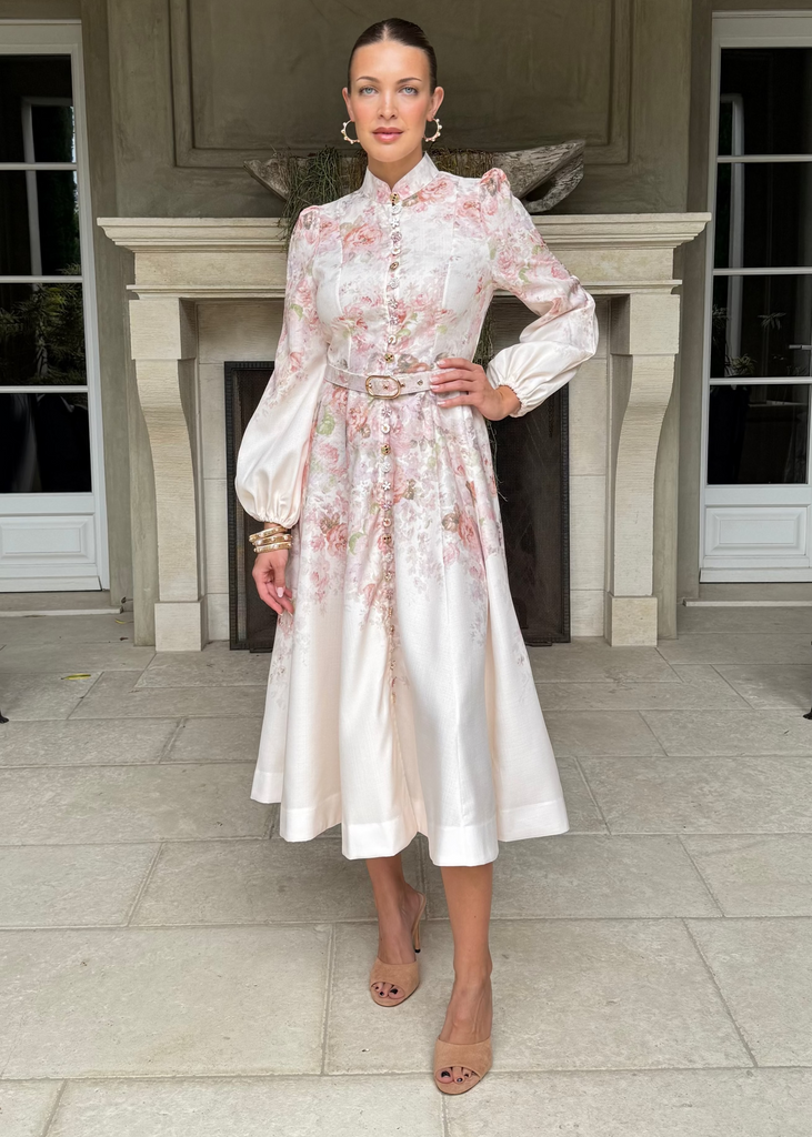 Woman in a floral dress standing in front of a building entrance.