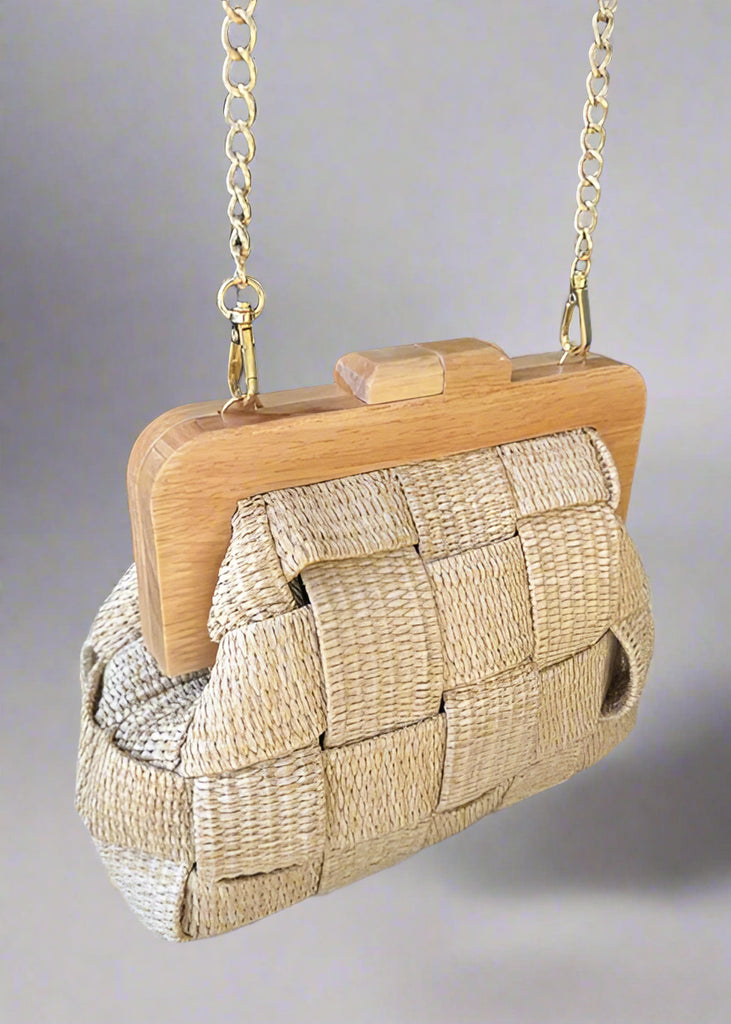 Woven handbag with wooden frame on a round platform in an indoor setting