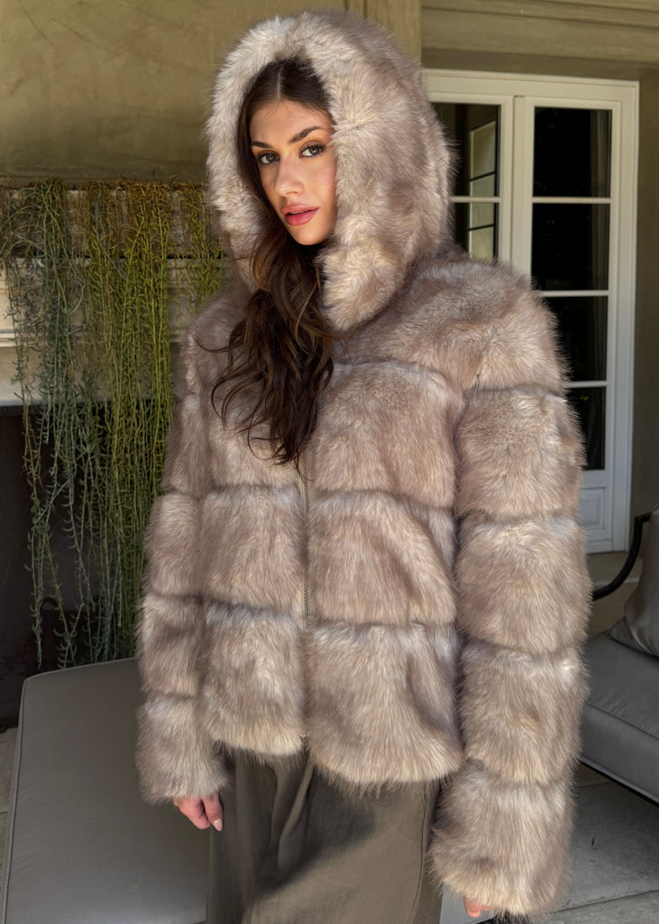 Woman wearing a fur coat with a hood in an indoor setting