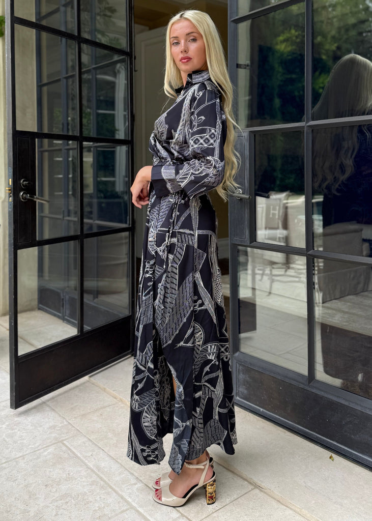 Woman in a patterned outfit standing in front of large glass doors.