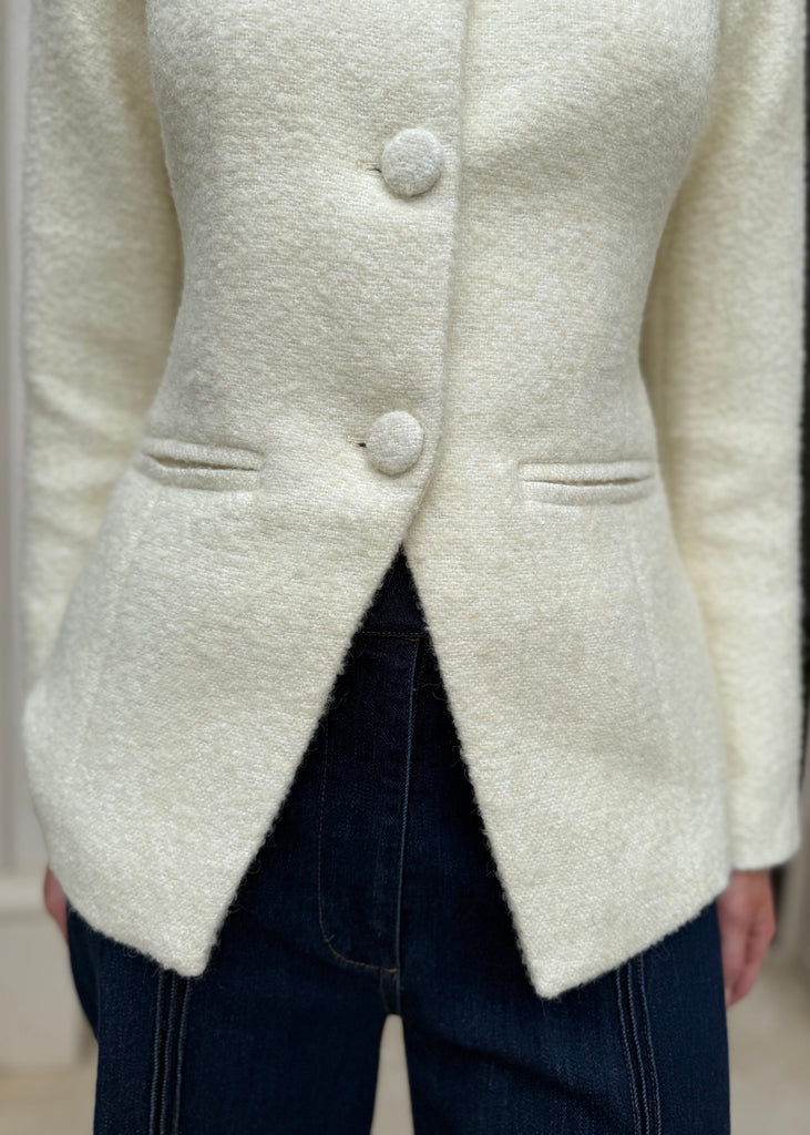 Close-up of a cream-colored cardigan with buttons on a neutral background