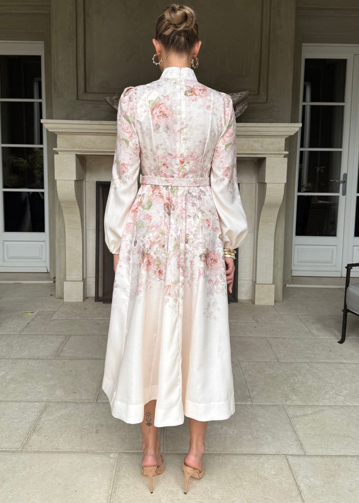 Woman in a floral dress standing in a elegant interior setting