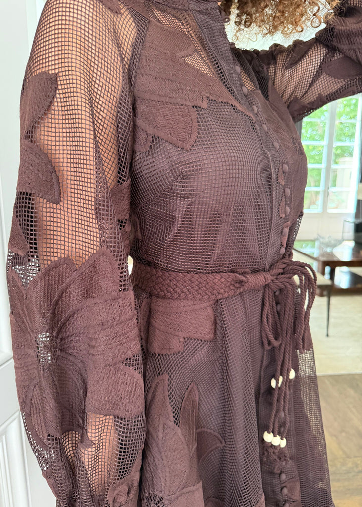 Brown sheer dress with floral patterns worn by a person indoors.