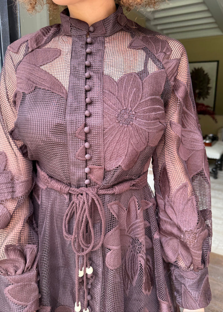 Close-up of a person wearing a sheer purple dress with floral patterns.