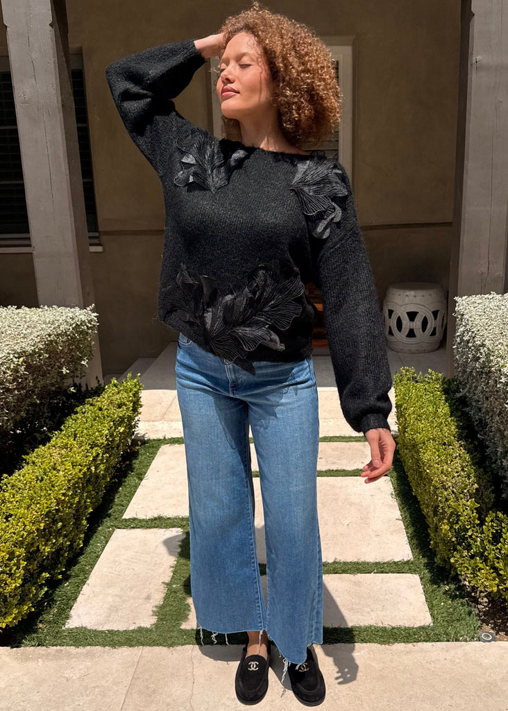 Woman standing in a garden with manicured hedges and a building in the background