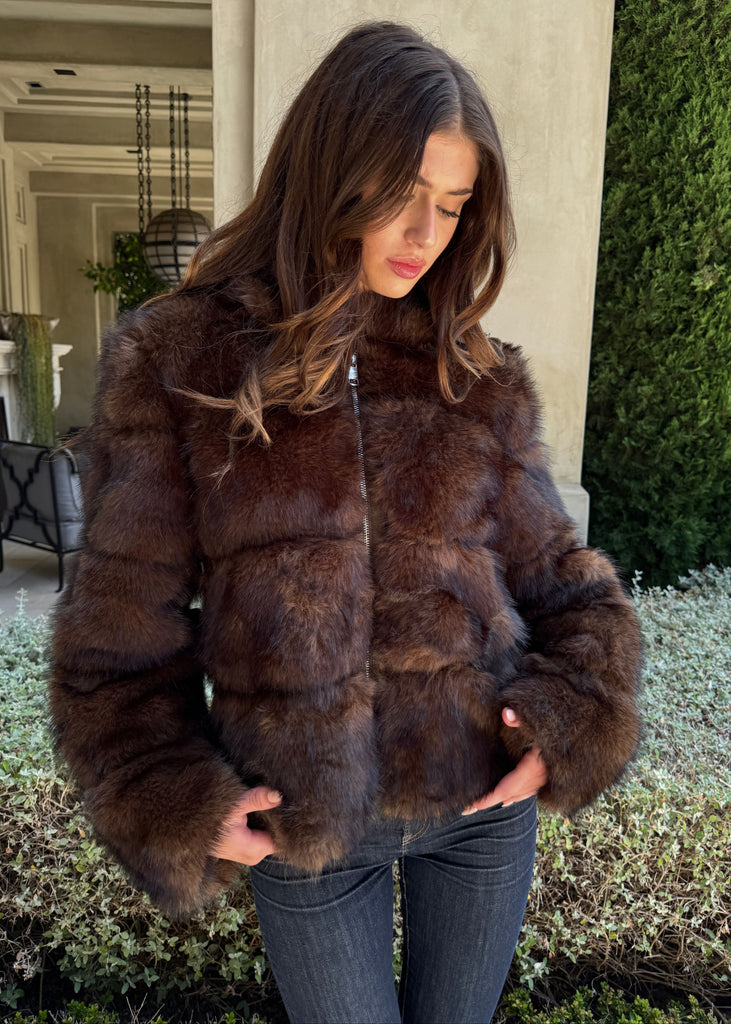 Woman wearing a brown fur jacket outdoors.