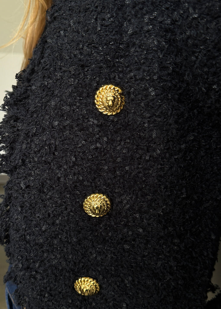 Close-up of a black textured garment with gold buttons.