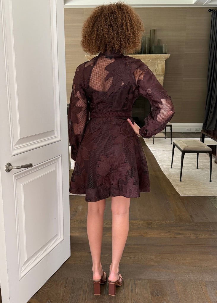 Person wearing a brown dress standing in a doorway of a home.