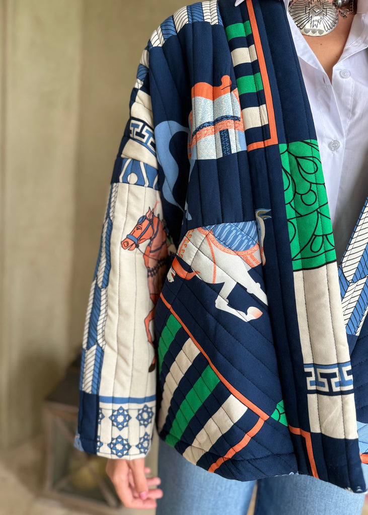 Person wearing a colorful quilted jacket with geometric and animal patterns.