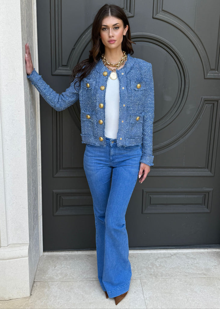 Woman in a blue outfit standing in front of a gray door.