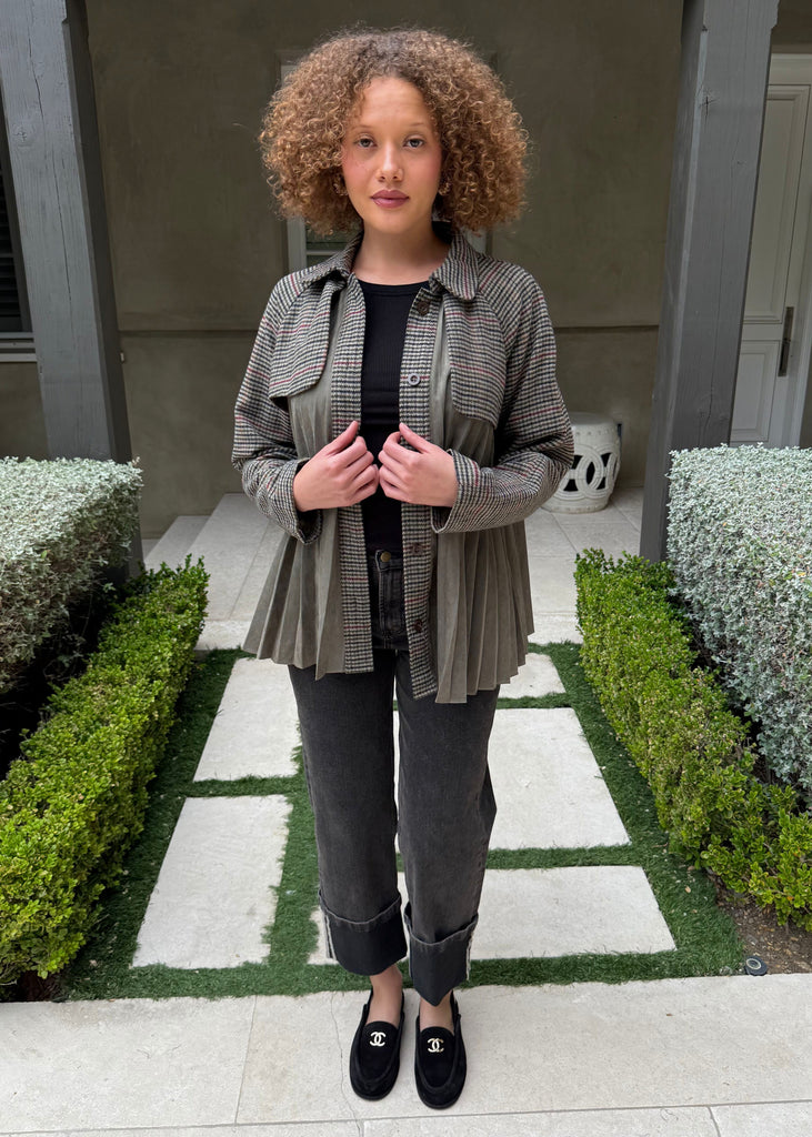 Woman standing in a garden with green bushes and a building in the background